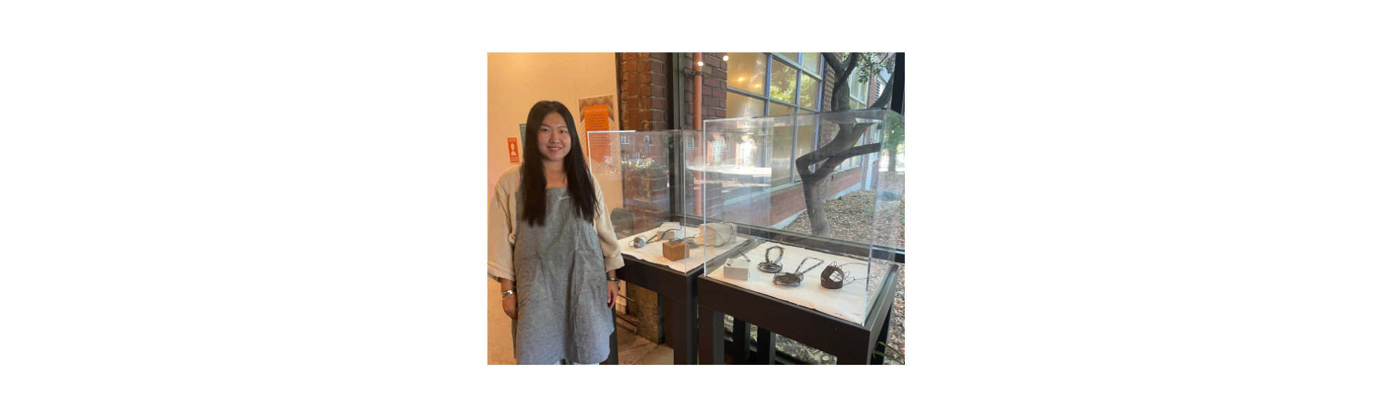 Younha Jung standing near a display of her artwork, at Pratt Fine Arts Center
